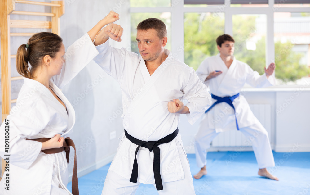 Obraz premium Woman and man in kimono sparring together in gym during karate training