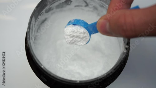 Close up of a hand scooping creatine with a scoop