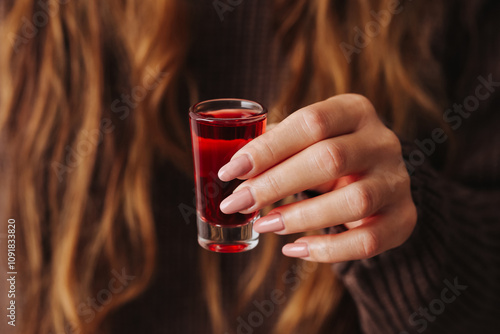 Canvas Print Girl holding a vodka shot with a vibrant red homemade cranberry liqueur