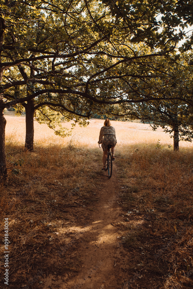 Fototapeta premium Woman riding bicycle in grass and autumn forest