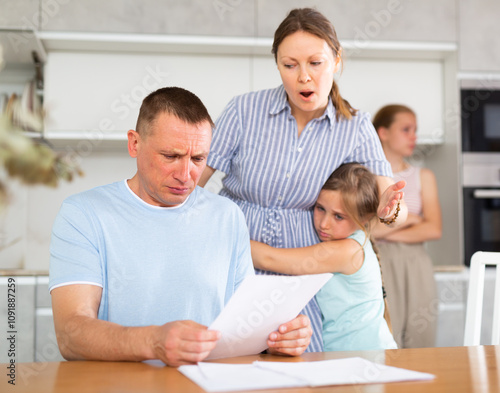 Wife yells at her husband who has not paid the loan. Children are upset and scared photo