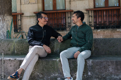 Momento espontáneo de risas y conexión entre dos hombres en un parque soleado.