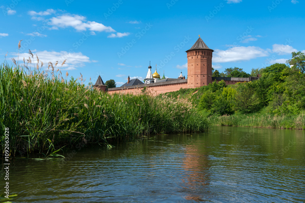 Fototapeta premium View of the Spaso-Evfimiev Monastery (a monastery of the Vladimir Diocese of the Russian Orthodox Church) on the bank of the Kamenka River on a sunny summer day, Suzdal, Vladimir region, Russia