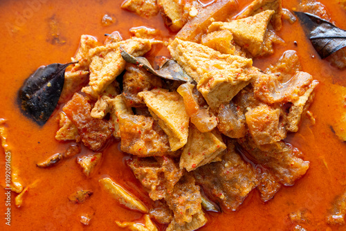 A flavorful Indonesian stew features tender pieces of tofu and aromatic spices simmered in a rich, vibrant red sauce, highlighting the culinary traditions of the region. photo