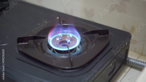 Man hand turning on the kitchen gas stove for cooking food. Gas stove with blue color flame.