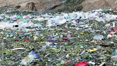 Near the shore, an excavator removes plastic waste as the waves keep bringing more debris. A powerful image highlighting human efforts against marine pollution photo