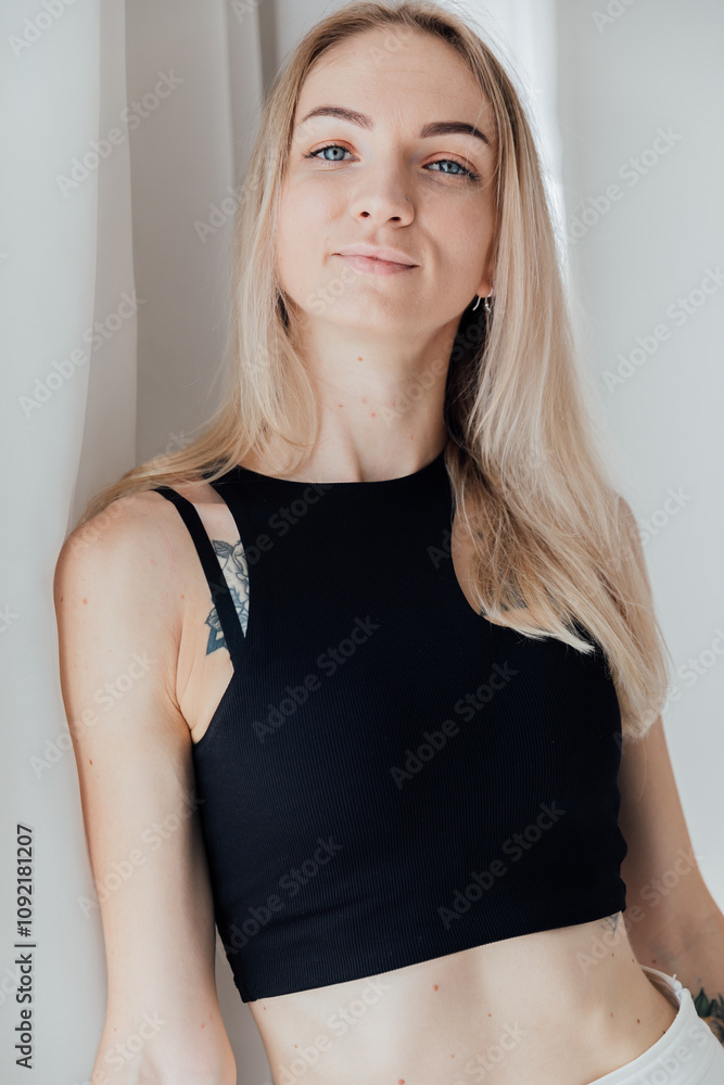 Fototapeta premium Portrait of a beautiful woman in a black swimsuit on the beach by the sea