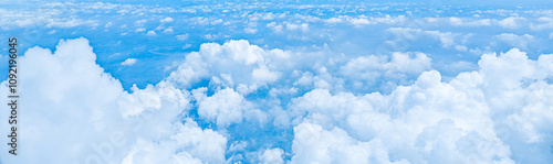 Aerial view of fluffy white clouds, captured from an airplane at high altitude. Scene for advertising, travel, aviation, exploration, nature, meteorology. Beautiful blue sky background