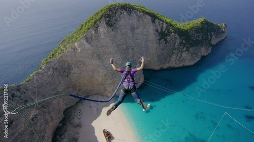 Brave leap off of Greece cliffside over beach, bungee jump in slow motion 