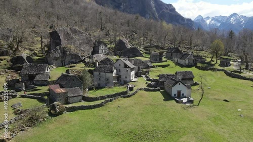 Ancient village showcasing charming stone houses nestled amidst a picturesque natural landscape in the swiss alps, Sabbione. Ticino, Switzerland, drone orbiting shot photo