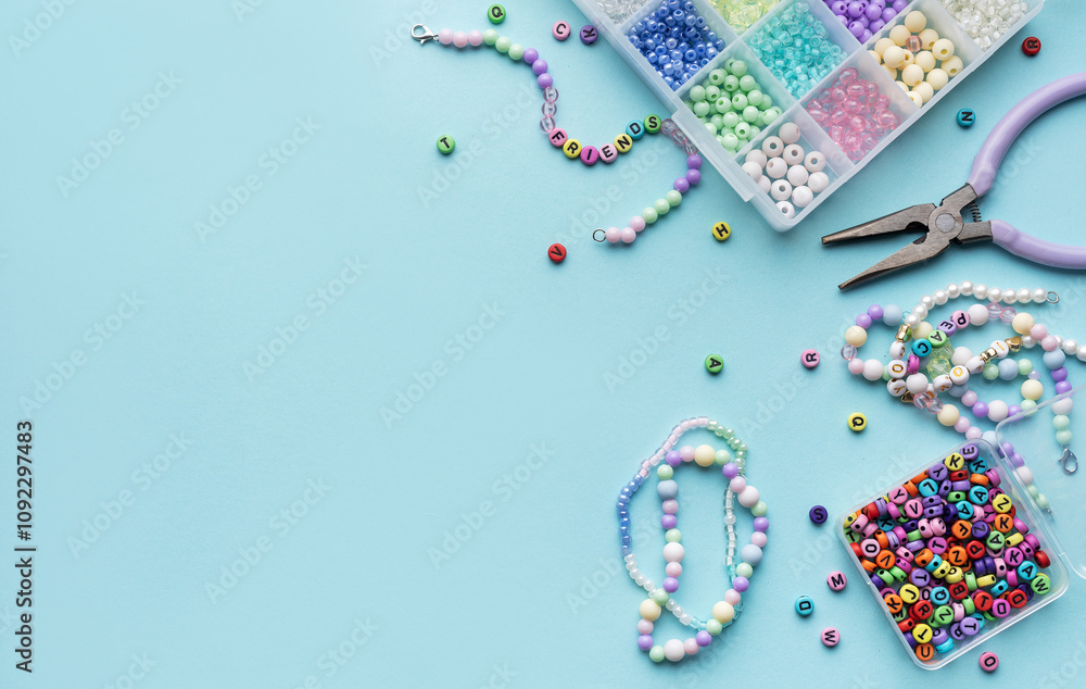 Colorful assortment of beads and jewelry-making tools on a blue surface with completed bracelets