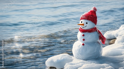 Festive and cheerful snowman with a red hat and scarf beside shimmering water, ideal for holiday card designs and winter-themed decorations. photo