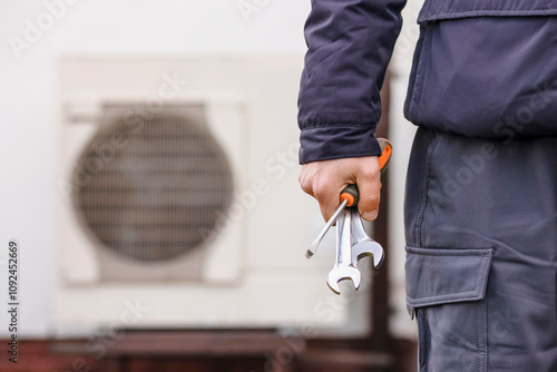 Heat Pump Heating System Installing and Maintenance. Worker Hand with Tools on Heat Pump Background. Heating and Cooling With Heat Pump.