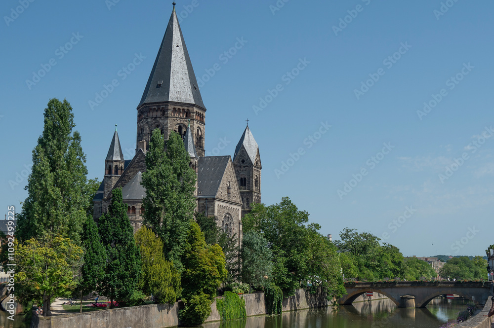 Le temple protestant à Metz avec la Moselle qui coule au premier plan, ciel bleu et soleil Le temple protestant à Metz avec la Moselle qui coule au premier plan, ciel bleu et soleil