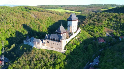 Journey through the majestic Karlstejn Castle, nestled in the lush hills of Czechia, showcasing its impressive architecture and surrounding nature during a beautiful sunny day.