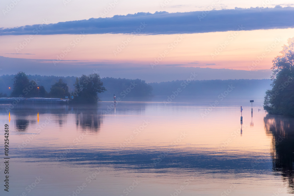Fototapeta premium Stiller See im Morgengrauen mit Bäumen und sanften Farben