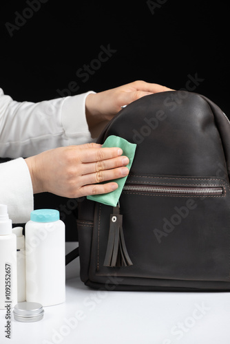 Cleaning the surface of a leather backpack with a cloth. Caring for leather accessories.