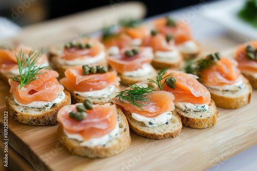 Mini smoked salmon blinis topped with cream cheese, dill, and a tiny lemon twist, arranged on a slate platter photo