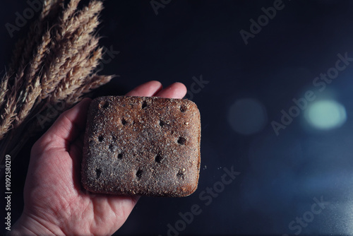 Fresh loaves of bread with wheat and gluten on a black table. Bakery and grocery concept. Fresh, healthy sorts of rye and white loaves food closeup. Fresh homemade bread with cereals. photo