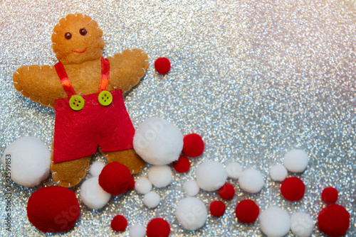 Silver glitter Christmas background with ginger cookie doll and decorations.