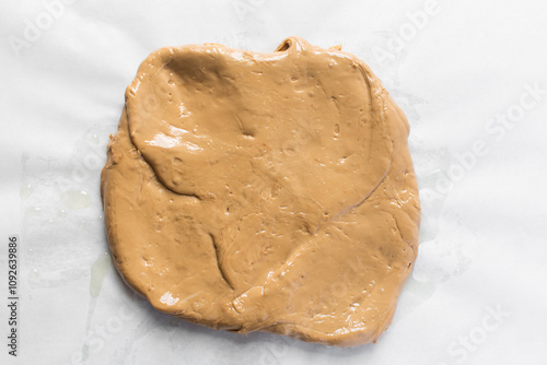 Overhead view of iloka candy on parchment paper, top view of cooked condensed milk candy shaped into a log, Nigerian iloka candy on a white background, process of making caramel hard candy photo