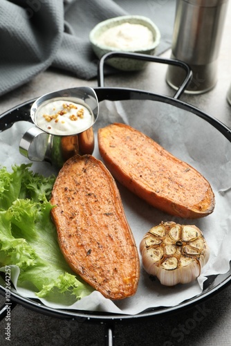 Tasty cooked sweet potato in baking dish served on grey textured table