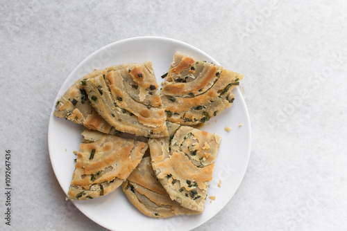 Overhead view of sliced chinese scallion pancakes on a white plate, top view of golden-brown homemade scallion pancakes, process of making cong you bing photo