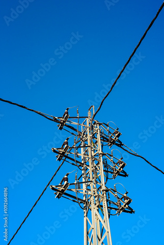Cables eléctricos en poste metálico  sobre cielo azul