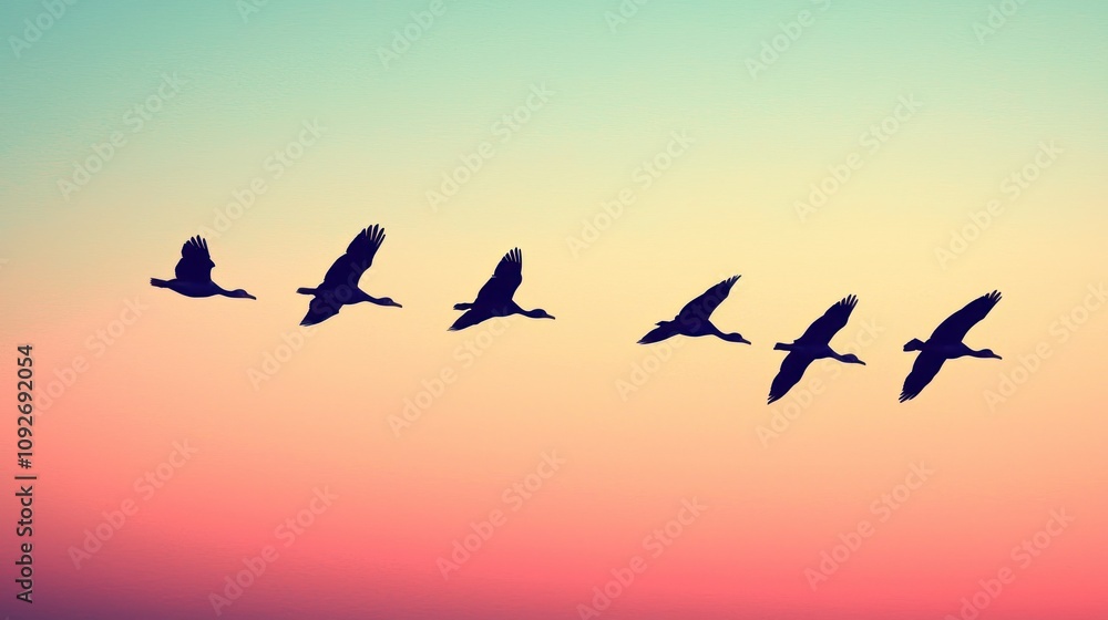 Fototapeta premium Silhouetted birds flying in formation against a vibrant sunset backdrop, creating a serene and picturesque scene.