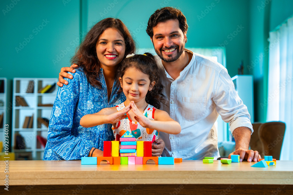 Smiling Indian asian parents and daughter building a toy house with wooden blocks at home Smiling Indian asian parents and daughter building a toy house with wooden blocks at home