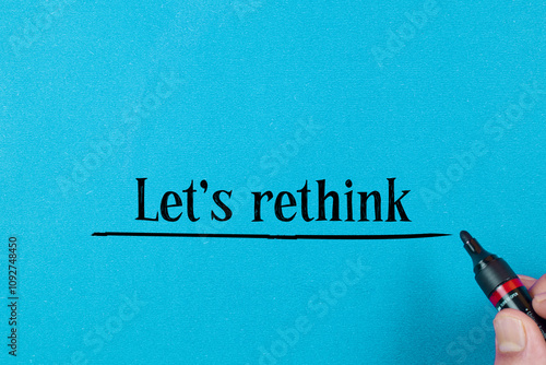 Concept words LET'S RETHINK written on blue background. Beautiful red table, red background. Businessman hand. Business concept. Copy space.