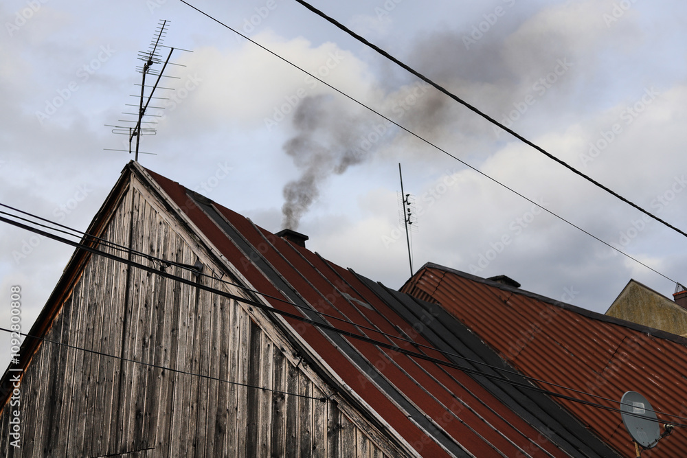 Nasty black smoke from burning garbage in the home furnace comes out of the house's chimney. Nasty black smoke from burning garbage in the home furnace comes out of the house's chimney.