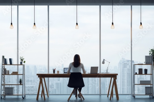 An individual focusing at a workspace by the window with a breathtaking view of the city skyline, representing productivity and ambition in a modern setting. photo