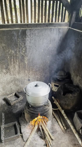 Footage of cooking water using aluminum kettles and wood charcoal fuel. Black aluminum kettle. Smoke partially covers the kettle