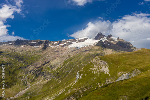 Val Veny scenic landscape in Courmayeur valley, Italy on Tour du Mont Blanc hiking route. Alps beautiful landscape, scenic view of the alpine peaks, green fields and meadow with flowers and blue sky photo