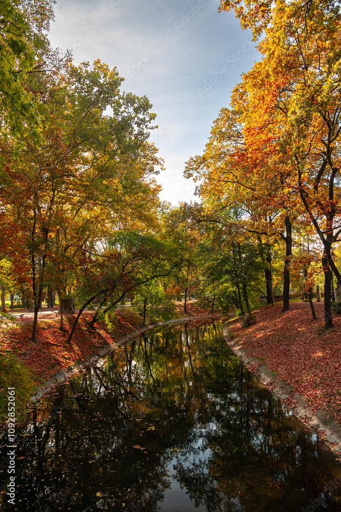 Budapest City Park (varosliget in Hungarian) during a beautiful autumn day, with orange vivid trees and lake in the middle of this park from Hungary. Sunny autumn day. Travel to Budapest. Budapest City Park (varosliget in Hungarian) during a beautiful autumn day, with orange vivid trees and lake in the middle of this park from Hungary. Sunny autumn day. Travel to Budapest.