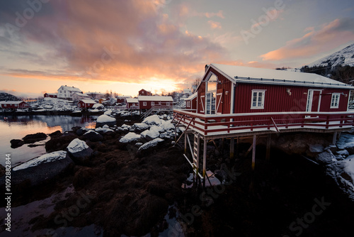 A breathtakingly beautiful sunset casting colors over the stunning red cabin by the tranquil water photo