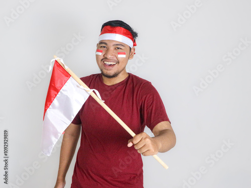 Excited young Asian men celebrate Indonesian independence day on 17 August by holding the Indonesian flag isolated over white background photo