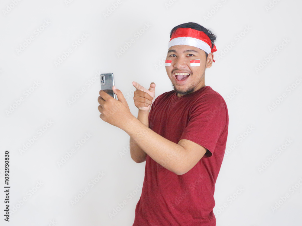 Excited young Asian men celebrate Indonesian independence day on 17 August while holding smartphone with blank screen isolated over white background Excited young Asian men celebrate Indonesian independence day on 17 August while holding smartphone with blank screen isolated over white background