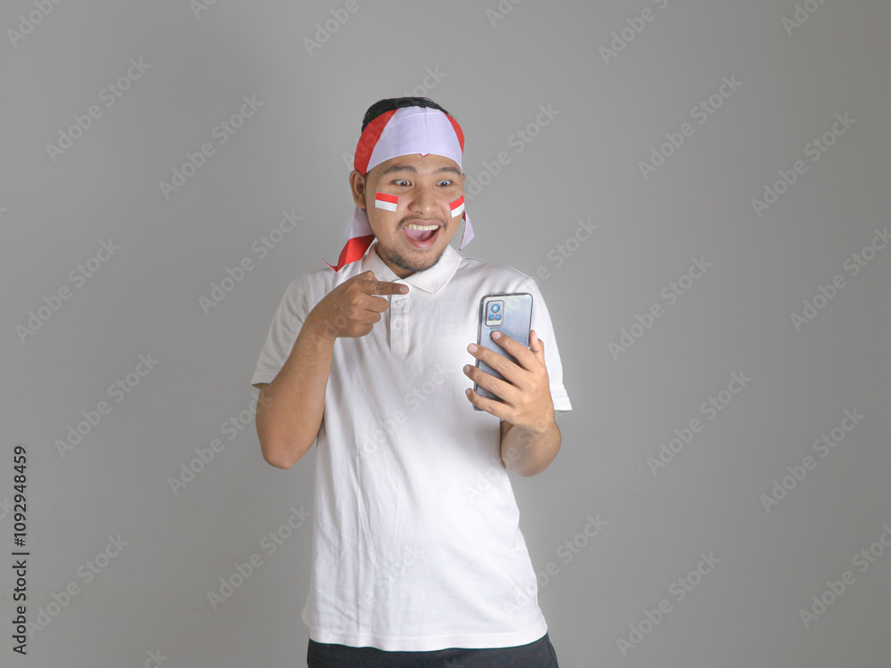 Excited and shock young Asian men celebrate Indonesian independence day on 17 August while holding mobile phone isolated over white background Excited and shock young Asian men celebrate Indonesian independence day on 17 August while holding mobile phone isolated over white background