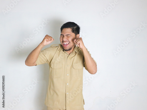 Asian male Indonesian civil servants wearing brown uniforms; usually called keki; look very happy by showing gestures of success in achieving something. Indonesian civil servants; ASN photo