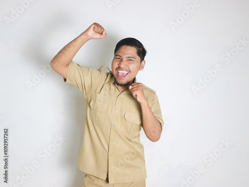 Asian male Indonesian civil servants wearing brown uniforms; usually called keki; look very happy by showing gestures of success in achieving something. Indonesian civil servants; ASN photo