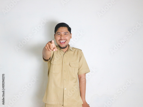 An Asian male Indonesian civil servant wearing a brown uniform who is usually called a keki is surprised while his hands are pointing forward. Indonesian PNS, ASN photo