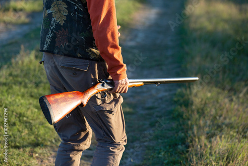 Mature hunter man holding a shotgun and walking through a field photo