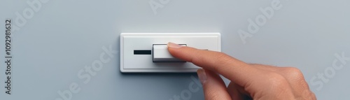 Close-up of a hand adjusting a sleek white dimmer switch on a wall, symbolizing energy control and modern home technology. photo