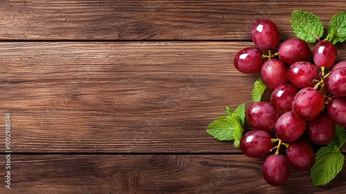 Fresh red grapes with mint leaves on rustic wooden background create vibrant and inviting display. glistening grapes add touch of elegance to any setting