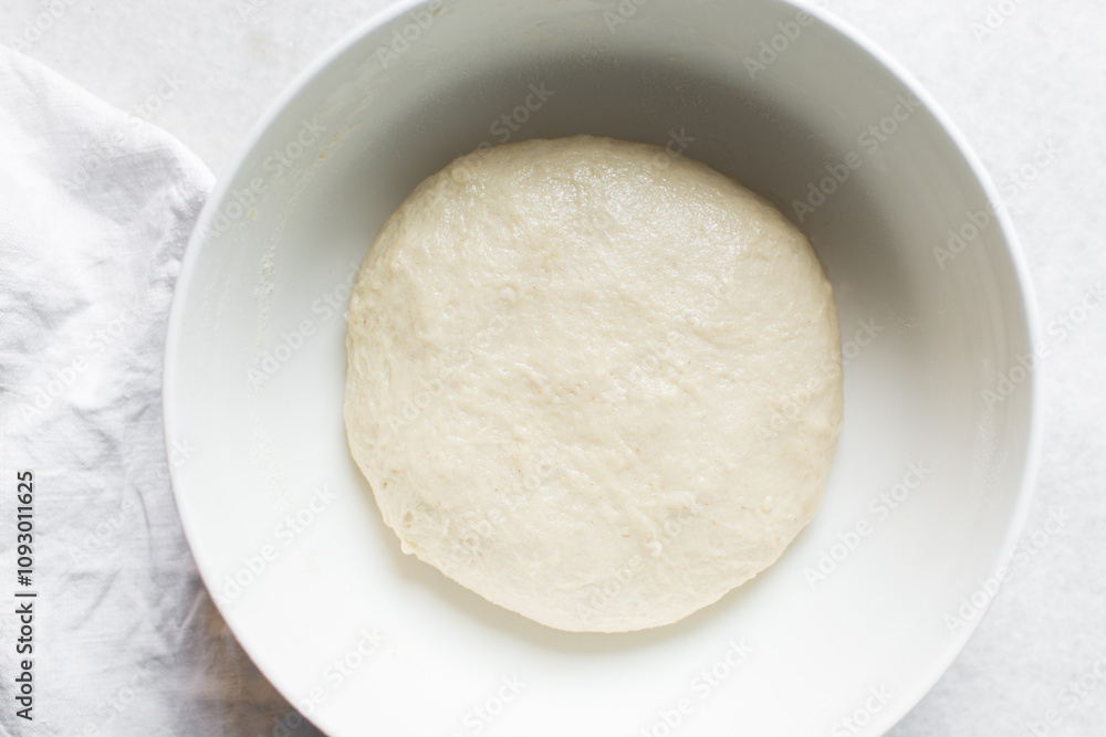 Overhead view of proofed challah dough in a white mixing bowl, top view of homemade challah dough rising in a white mixing bowl, process of making challah Overhead view of proofed challah dough in a white mixing bowl, top view of homemade challah dough rising in a white mixing bowl, process of making challah