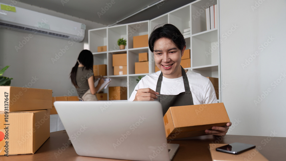Young Couple Managing Online Business and Checking Product Inventory from Home Office with Laptop and Packaging Boxes Young Couple Managing Online Business and Checking Product Inventory from Home Office with Laptop and Packaging Boxes