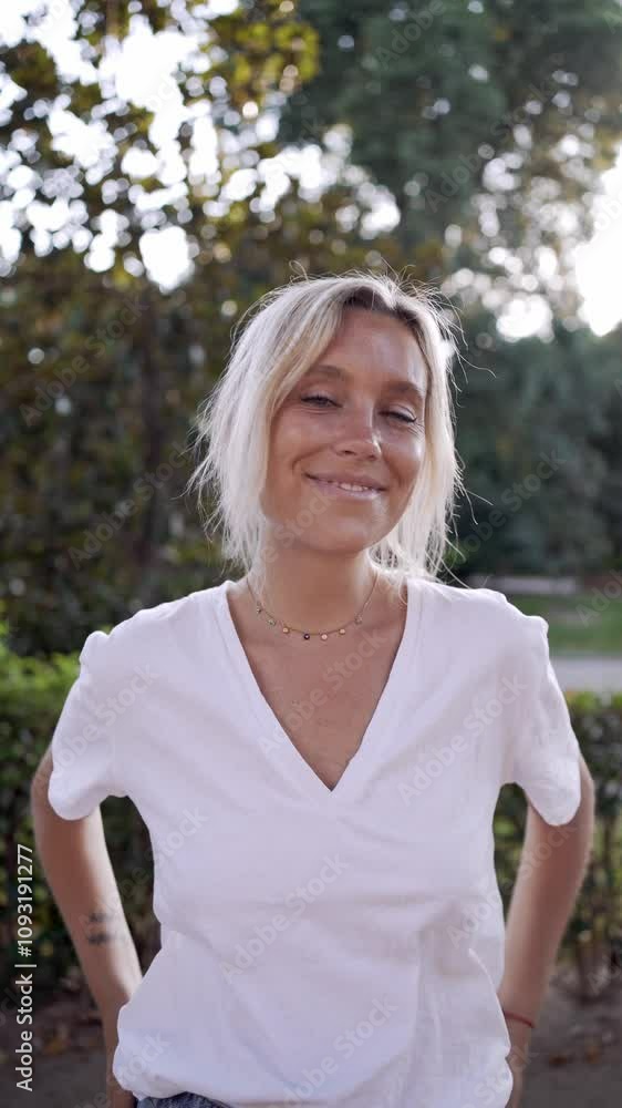 Young woman posing in a park, gradually smiling and radiating happiness, showcasing a joyful and cheerful expression Young woman posing in a park, gradually smiling and radiating happiness, showcasing a joyful and cheerful expression