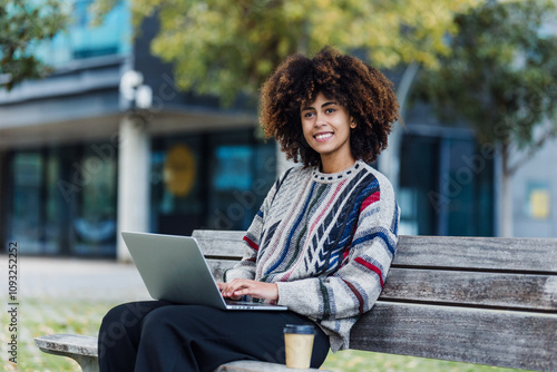 young African American student woman using laptop or computer in city of Spain Europe, Hispanic and caribbean people with afro hair in university campus 